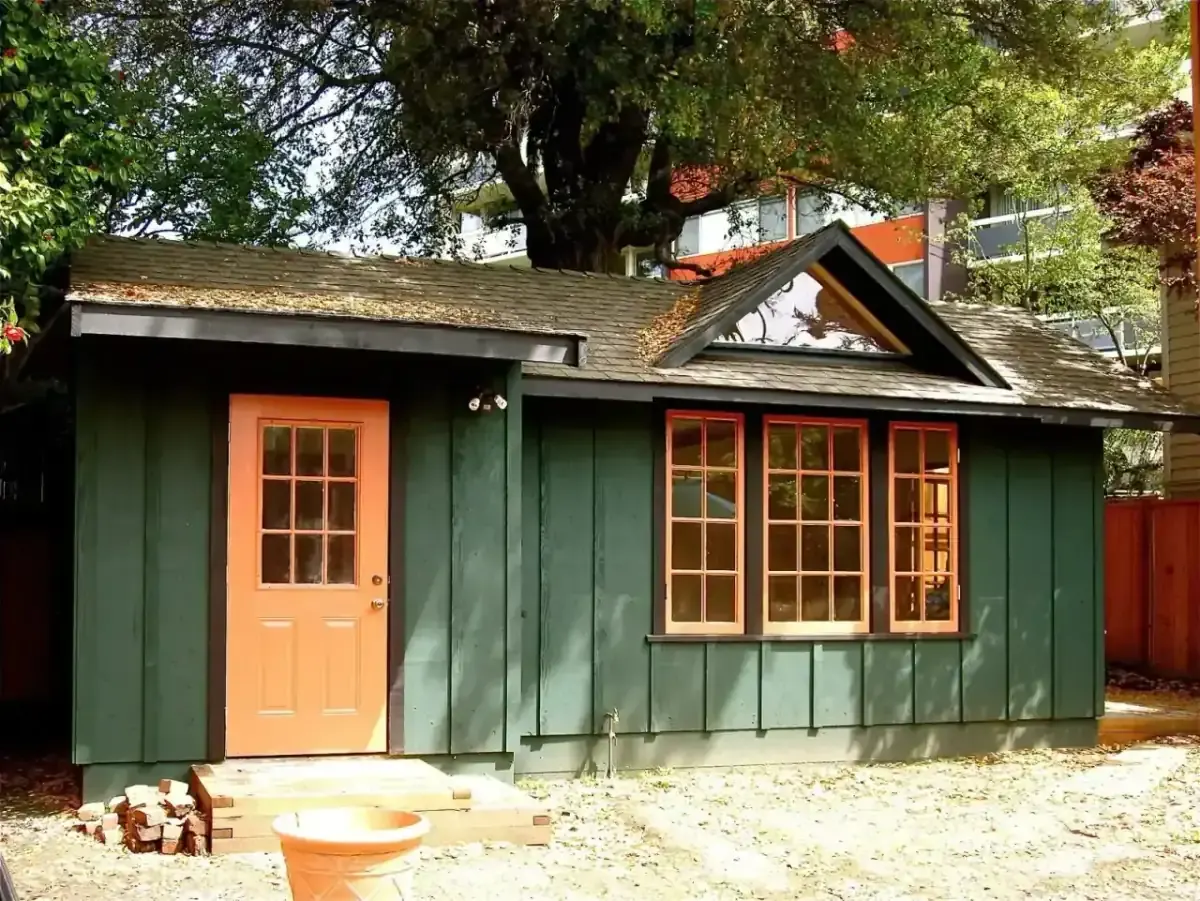 A custom board-and-batten ADU by John Kinstle, with red-trimmed windows and a craftsman gable